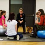 siedząca kobieta na dużej niebieskiej piłce