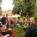 Duża grupa dzieci siedząca na trawie.