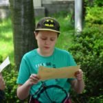 chłopczyk w czapce ze znakiem batmana trzyma w rękach kartkę papieru