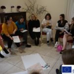 grupa kobiet siedząca w kręgu z kartkami w ręku