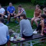 grupa osób siedząca w kręgu przy ognisku