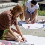 młoda kobieta nakleja wycinek z gazety na duży arkusz białego papieru