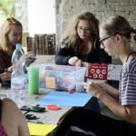 kilka kobiet lepi z plasteliny wspólnie przy stole