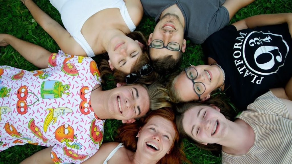 grupa osób leży w kręgu na ziemi głowami do siebie